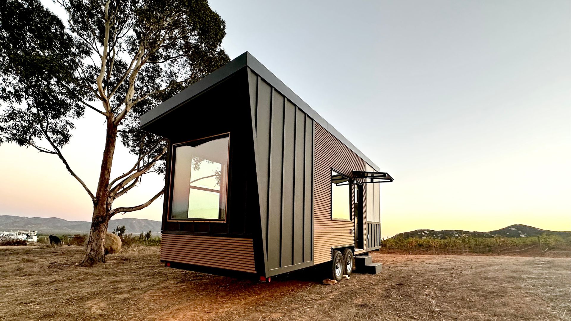 A completed modern tiny home in a rought, natural setting.