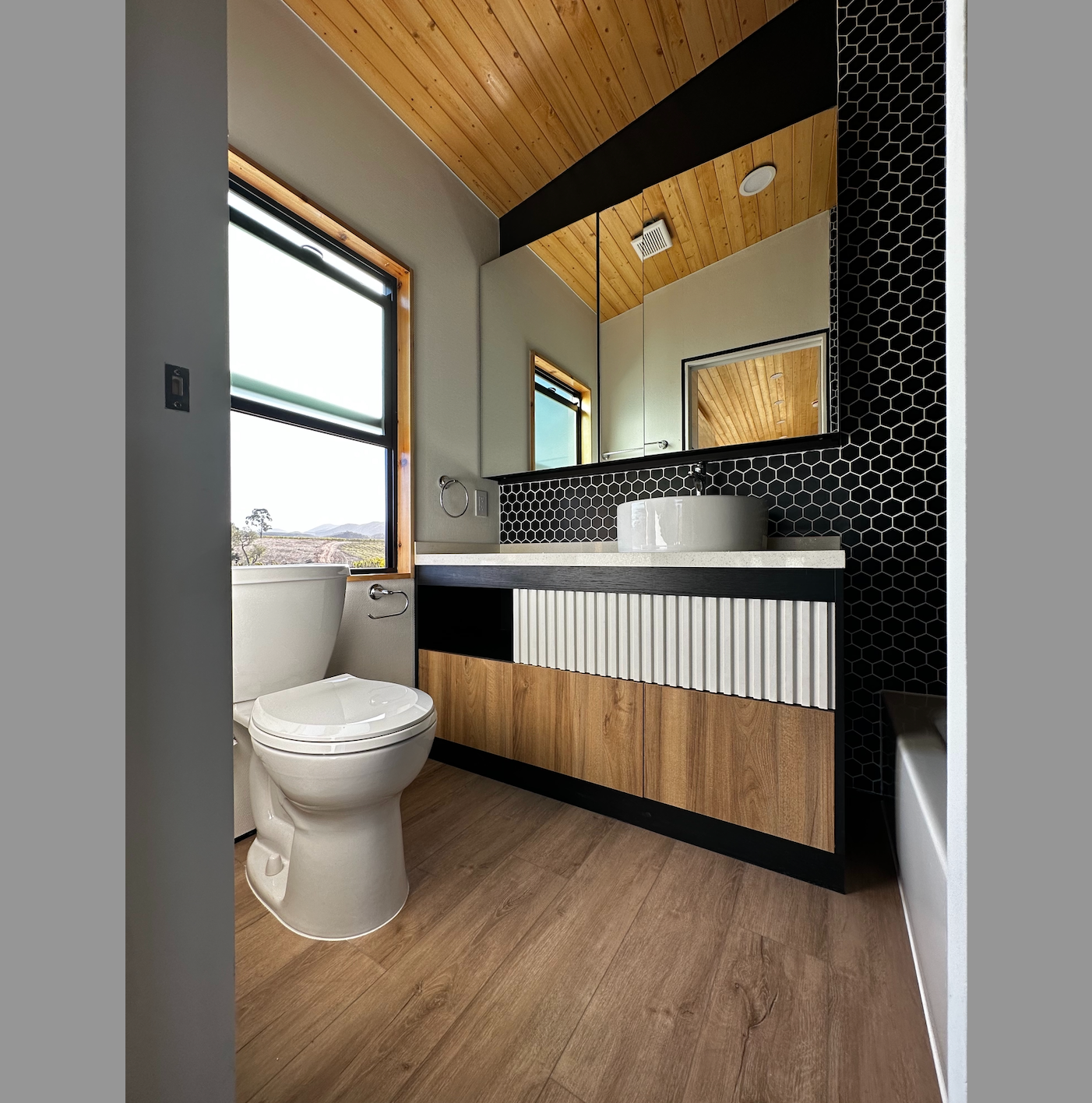 A large mirror in in a modern tiny home gives the bathroom a more open, airy feel.