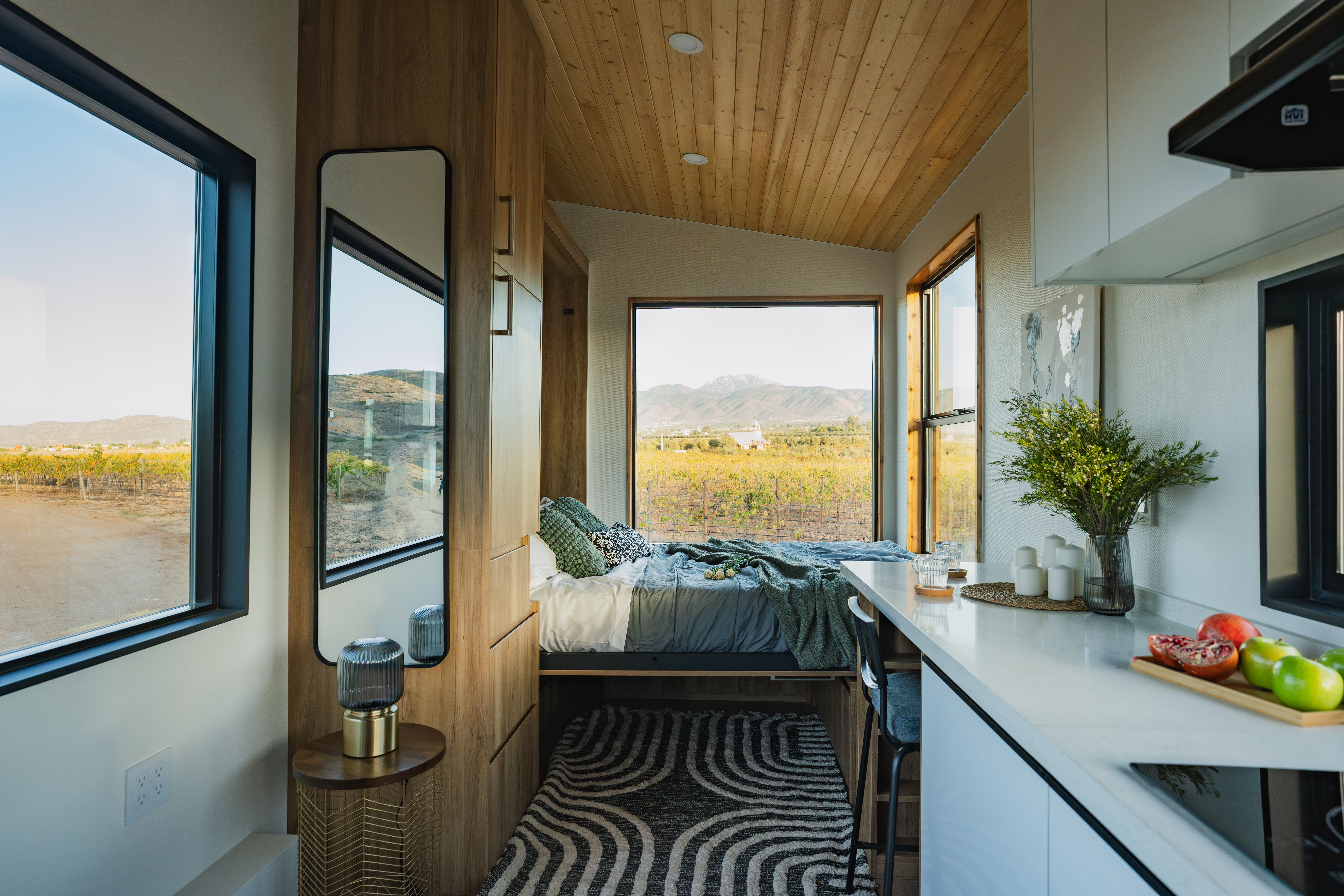 Clever S tiny home interior with kitchen, Murphy bed, and large windows