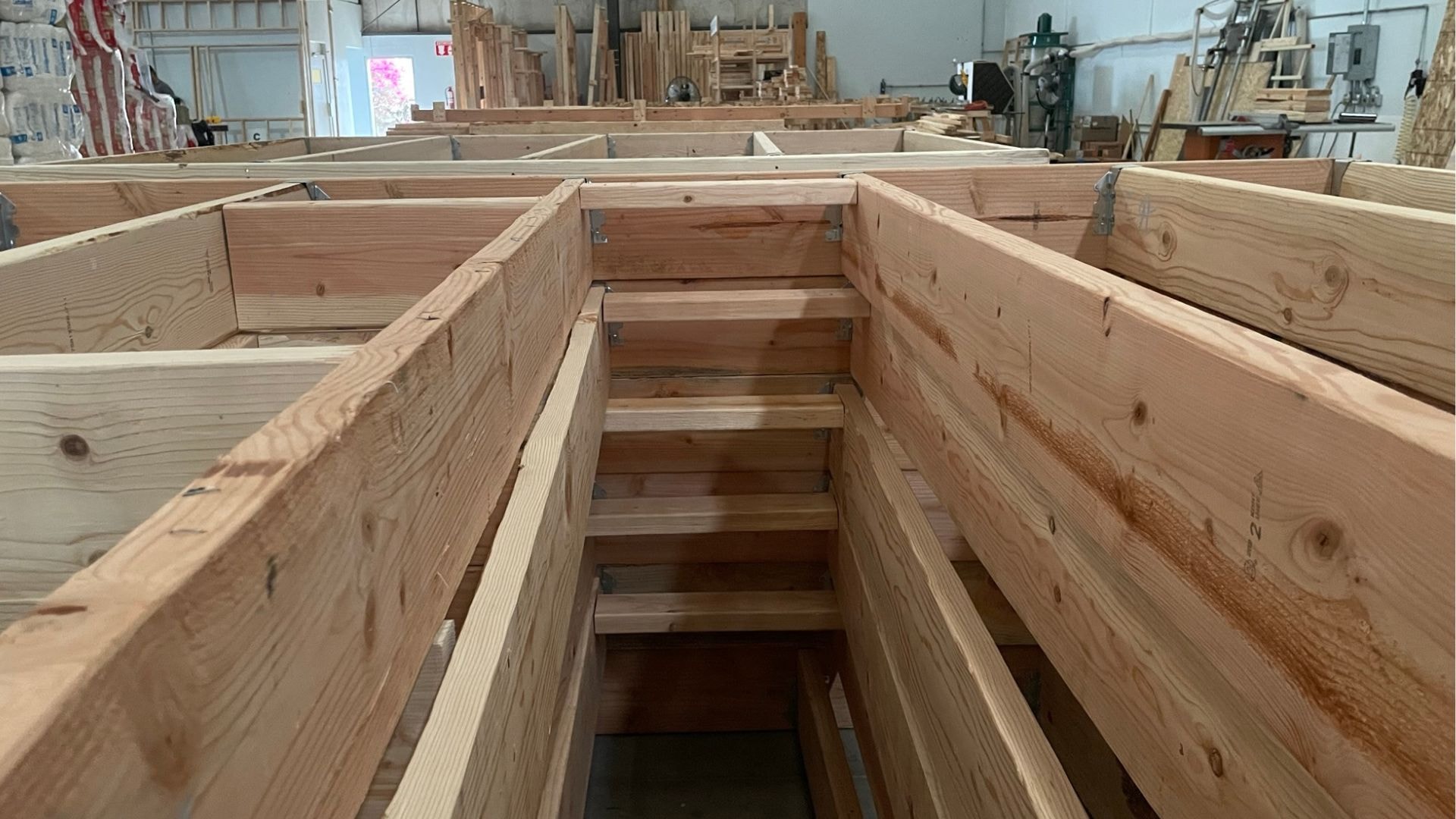 A wooden wall template used at Clever Tiny Homes, neatly arranged on a factory floor.