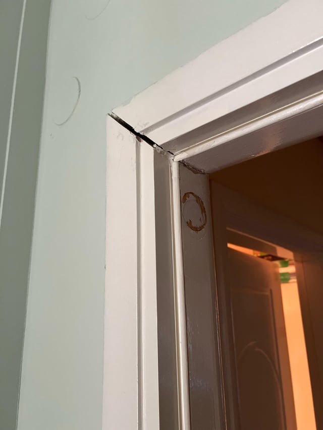 Photo of a door frame with obvious cracks on its trim details.