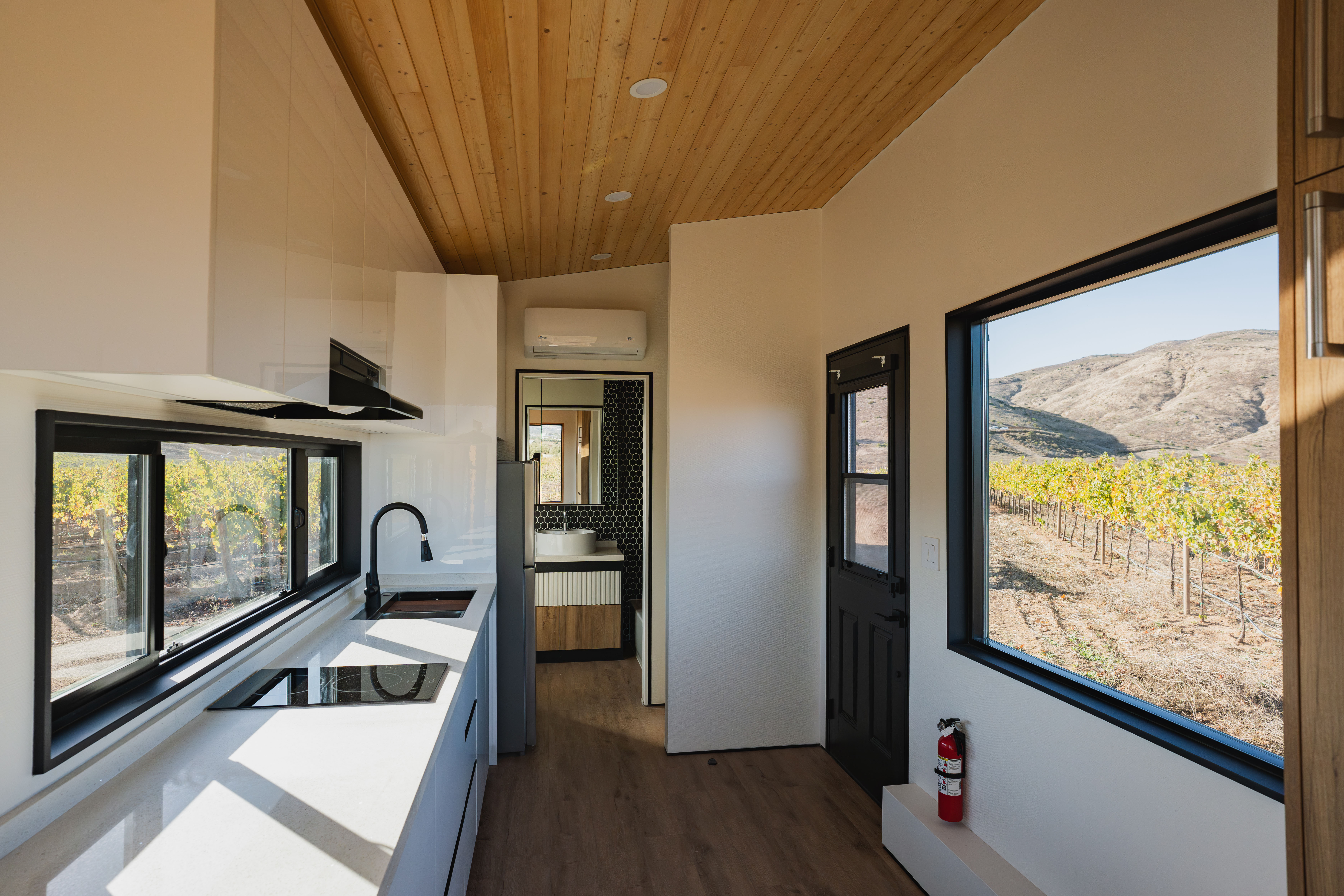 Clever S tiny home interior with kitchen, Murphy bed, and large windows