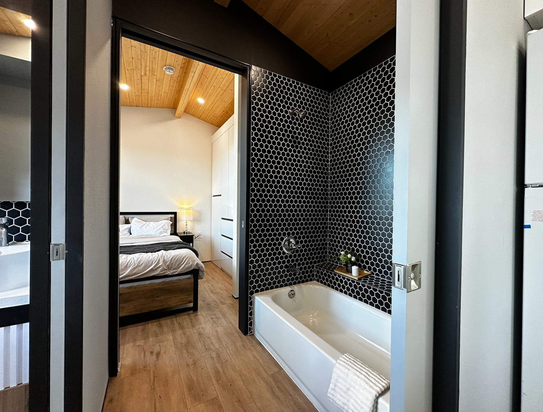 A modern tiny home featuring a high ceiling, real tiles, and a bathtub, creating a spa-like atmosphere.