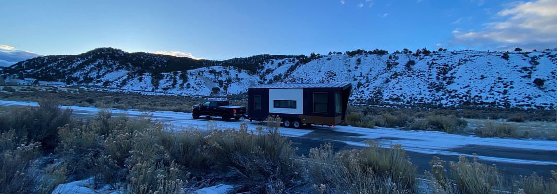 Photo of a Clever tiny home on wheels being towed through snow