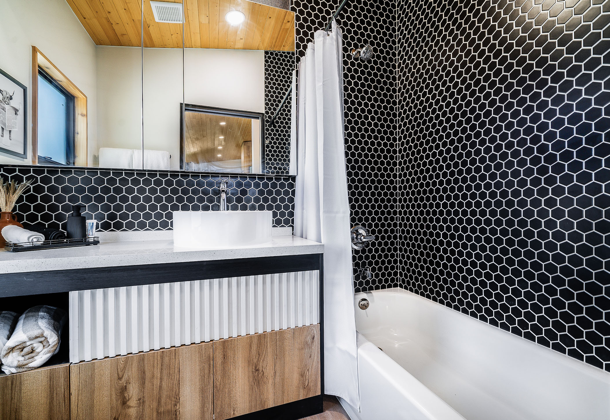 A Clever S bathtub and shower with large vanity and medicine cabinet.