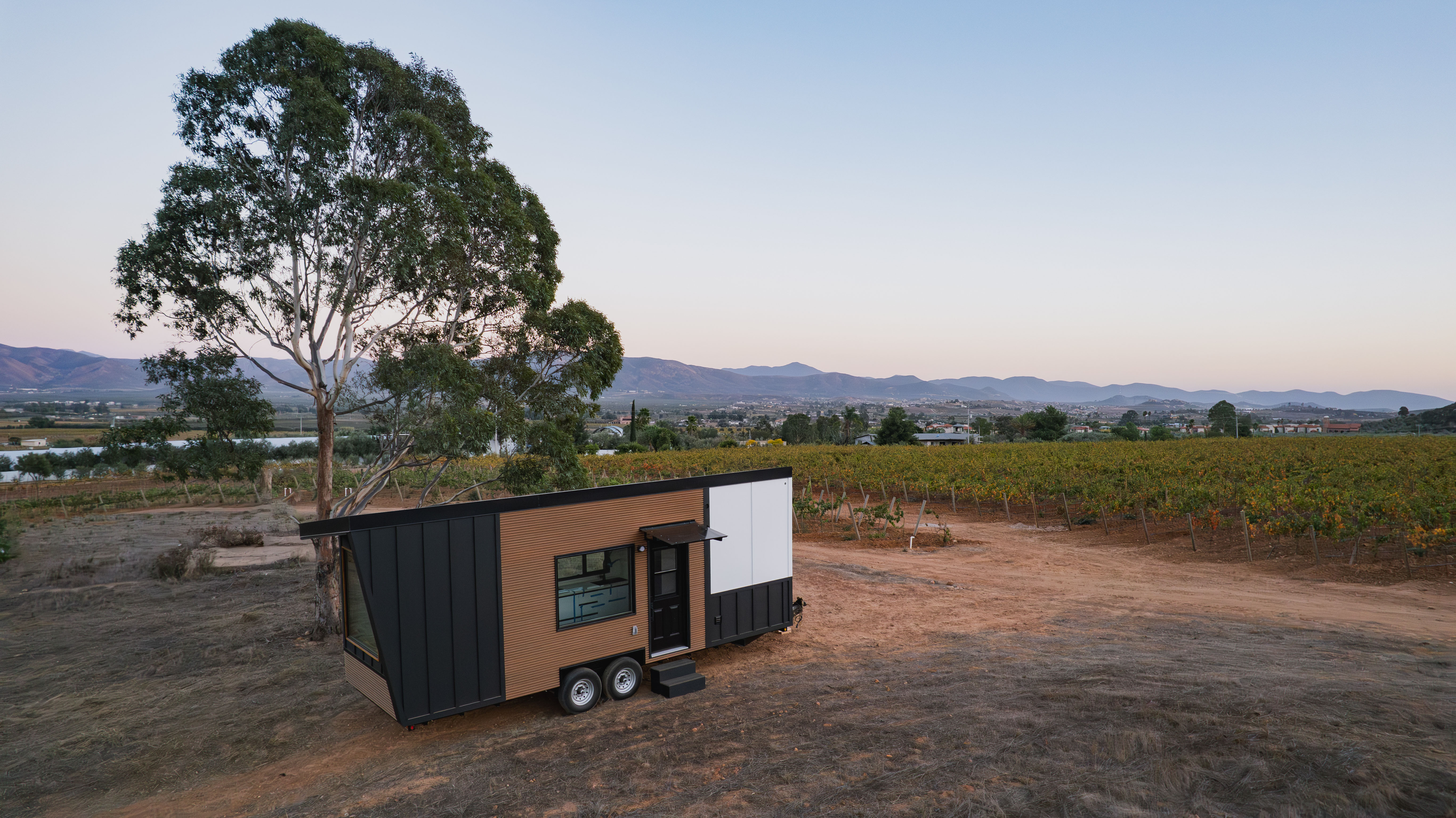 A tiny home on wheels parked in a vineyard