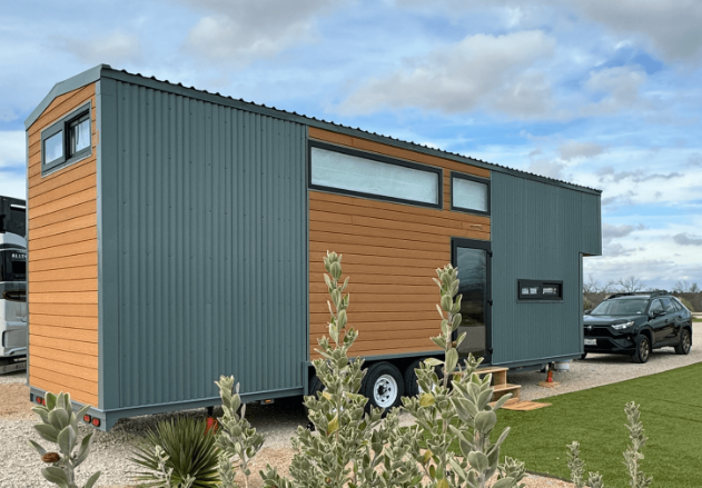 Handcrafted Tiny Topanga home parked in Malibu with wood siding and large picture window reflecting coastal light.