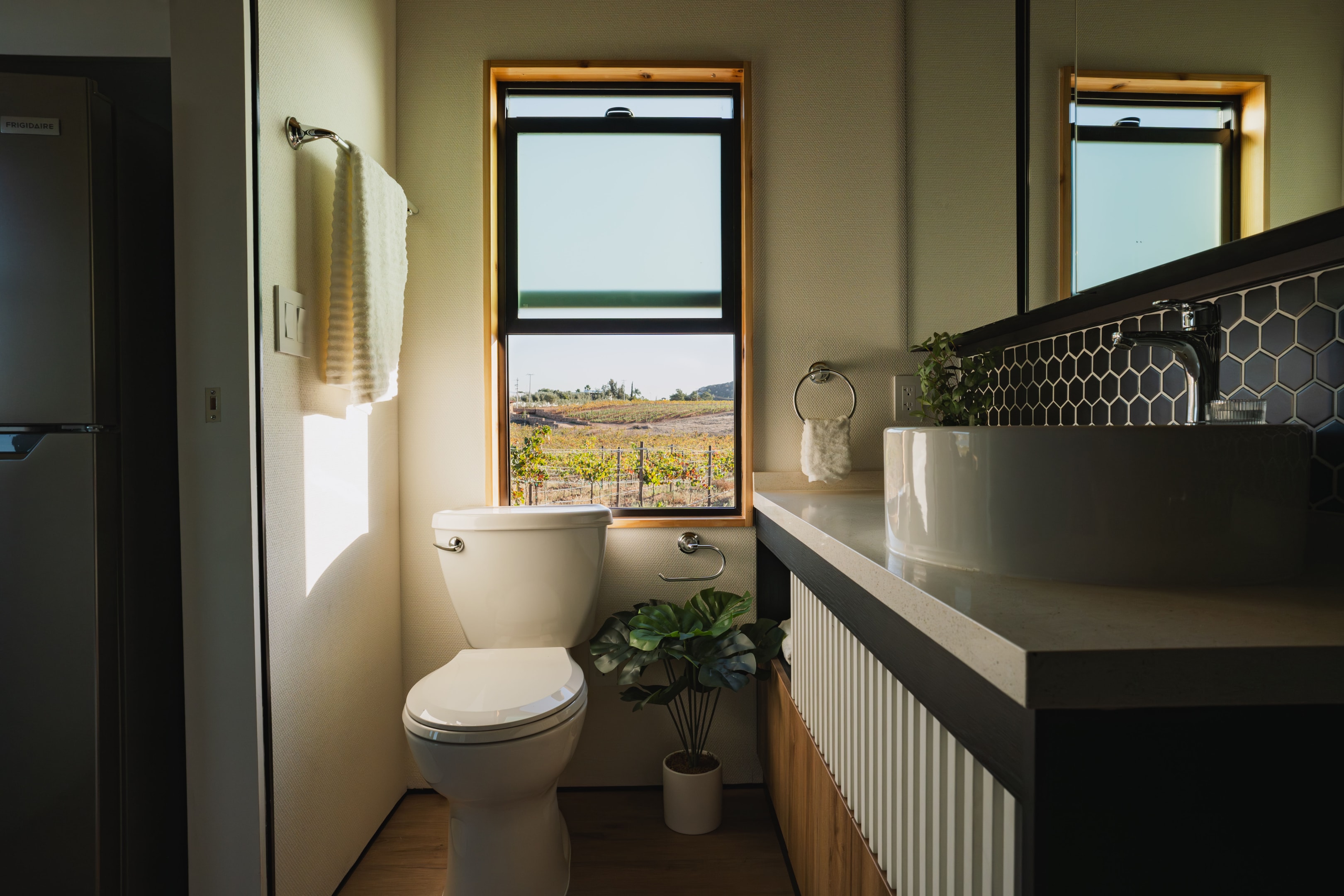 Luxury tiny home bathroom with large vanity, medicine cabinet with mirror and a standard flush toilet. 