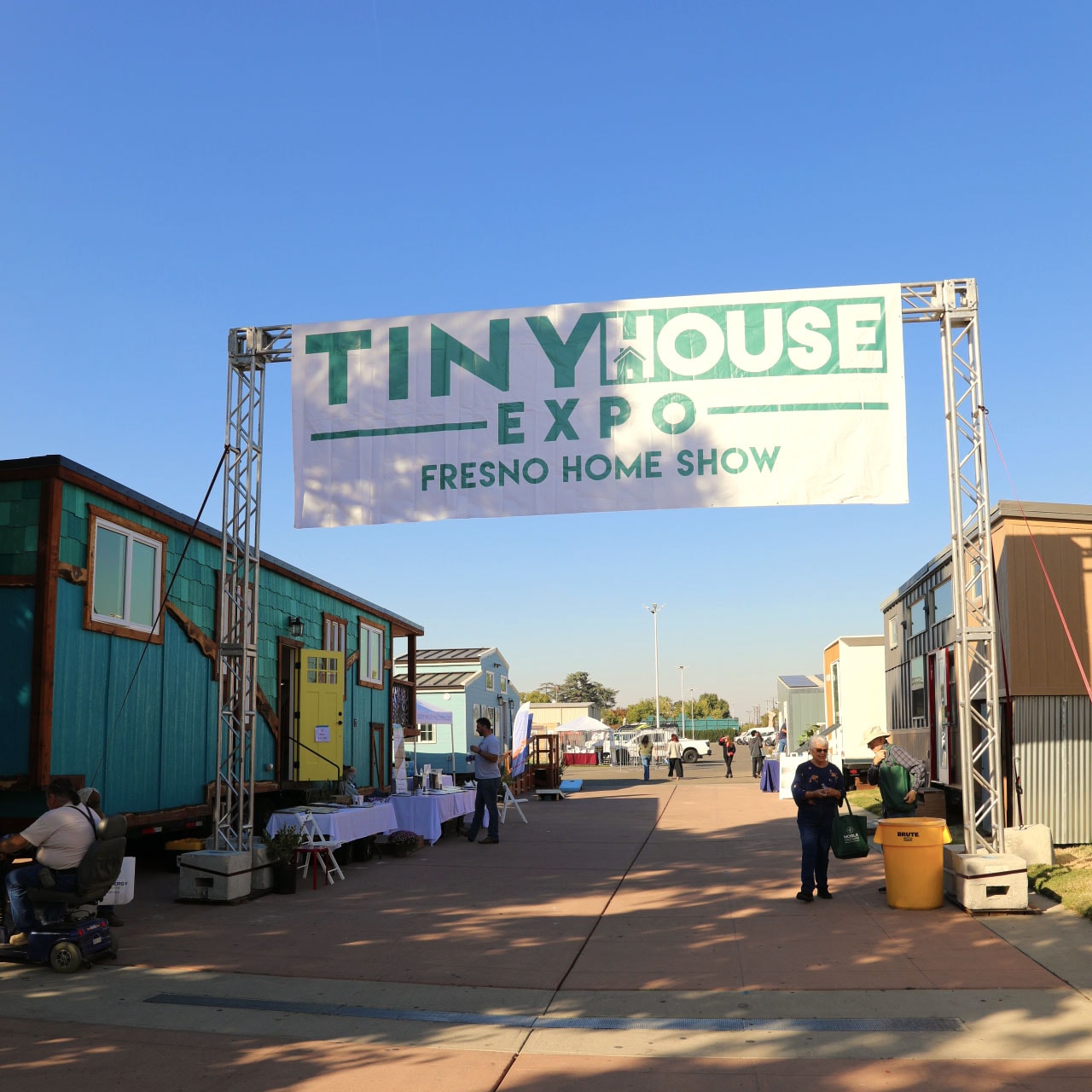 Photo of a tiny house expo in Fresno, California, a large banner of the event displayed at the entrance.