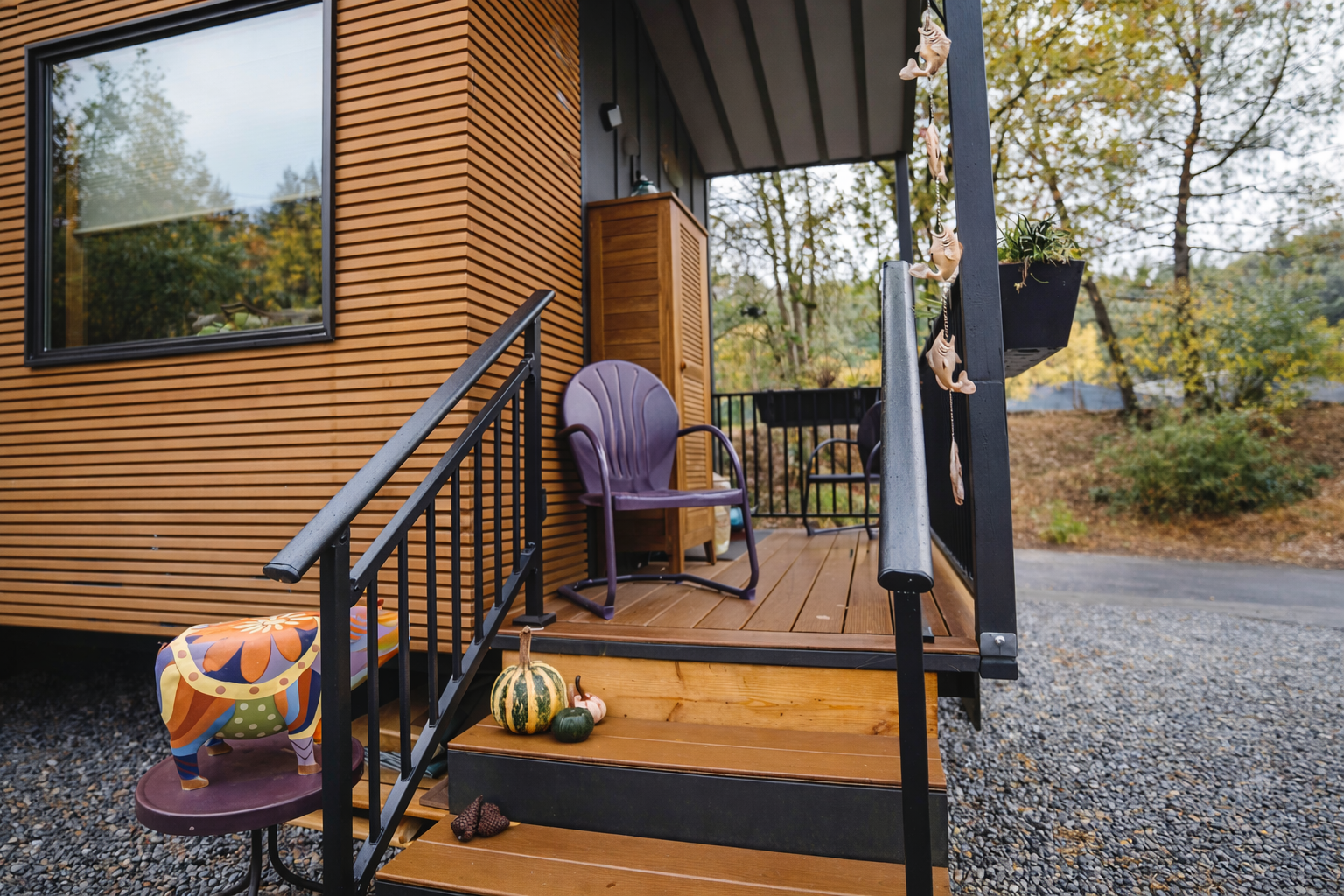 Photo: Clever porch with slatted wood cabinet, chair, and personal touches.