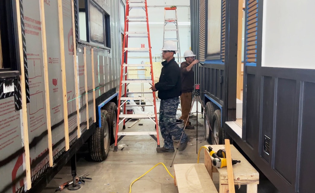 Men at work on unfinished sidings at a Clever Tiny Home factory